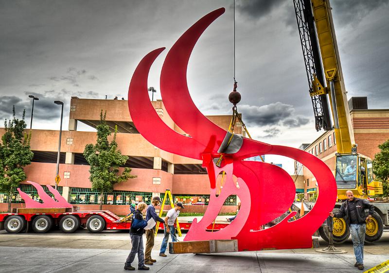 A heavy crane lowers the first flame into place